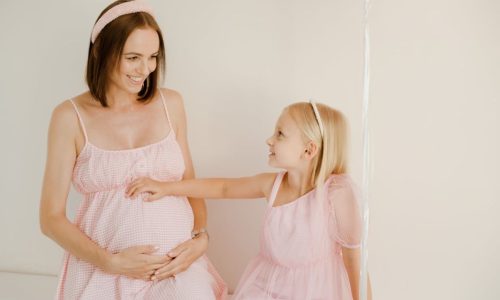 Mädchen berührt den Bauch der schwangeren Mutter